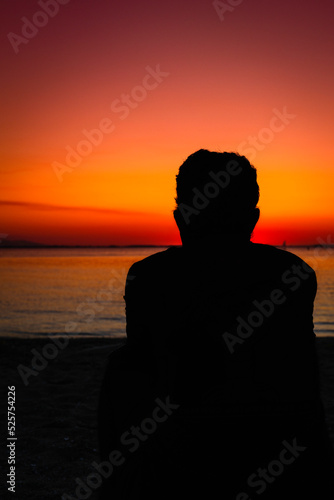 silhouette of a person sitting on the beach at sunset