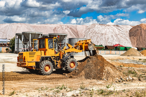 A large front loader pours sand into a pile at a construction site. Transportation of bulk materials. Construction equipment. Bulk cargo transportation. Excavation. © Anoo
