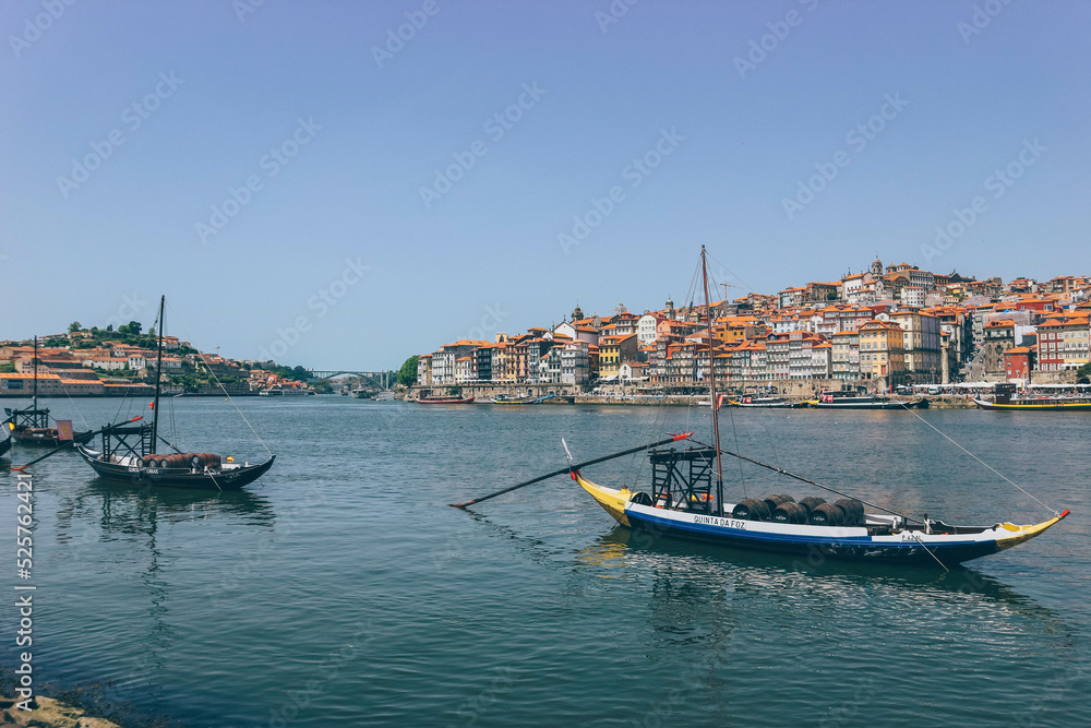 Old wooden boats over the calm river and the city behind in Porto 