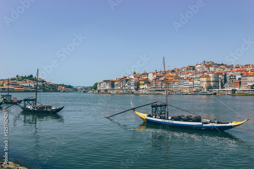 Old wooden boats over the calm river and the city behind in Porto 