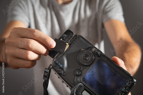 Photographer holding memory card insert DSLR camera.
