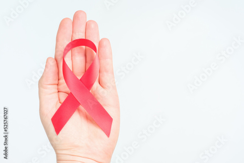 A female hand holds red ribbon, the international day against AIDS and hiv.