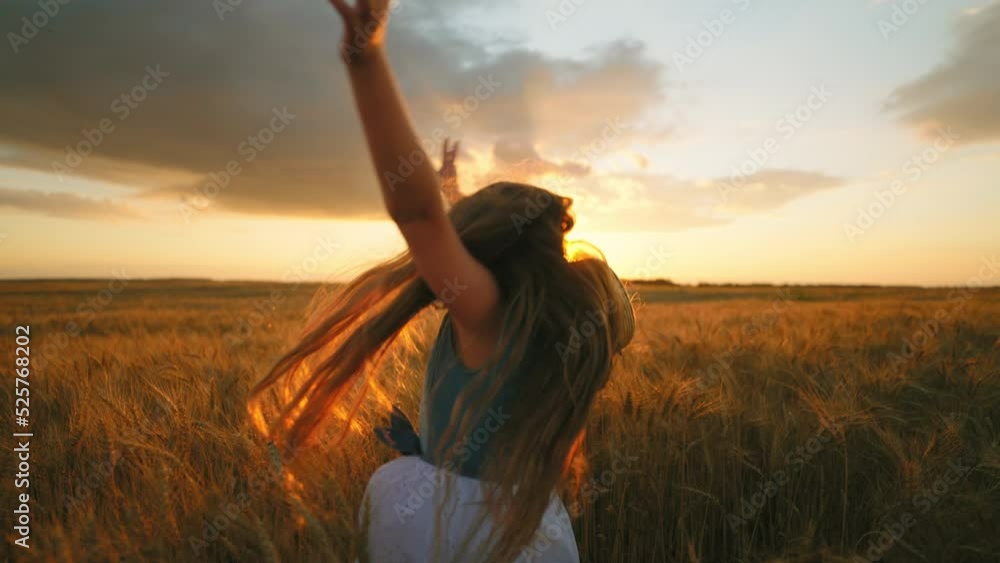 carefree and joyful little girl with long loose hair is whirling and jumping in golden wheat fields carefree and joyful little girl with long loose hair is whirling and jumping in golden wheat fields