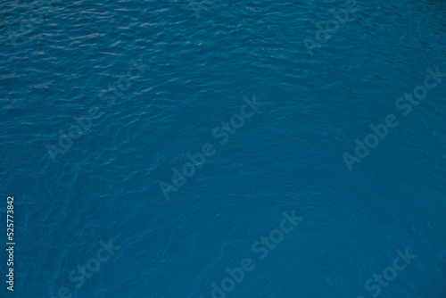 Blue and bright water surface with sun refection in swimming pool for background