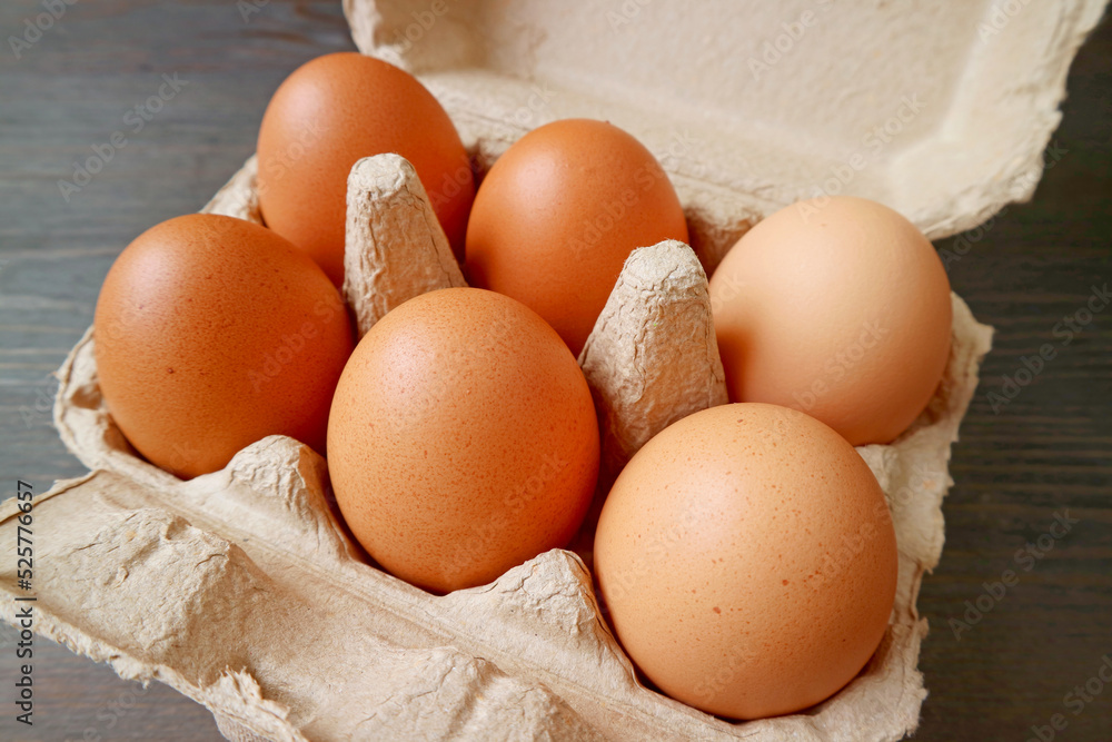Organic Chicken Eggs in Paper Carton Box on Black Wooden Background Organic Chicken Eggs in Paper Carton Box on Black Wooden Background