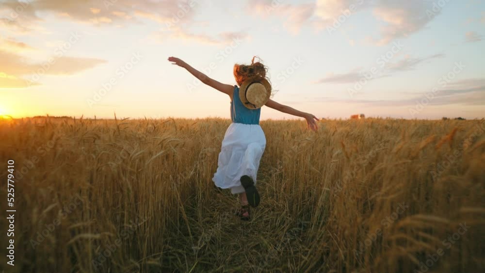 happy little girl is running on golden wheat fields in summer vacation, sunset in countryside