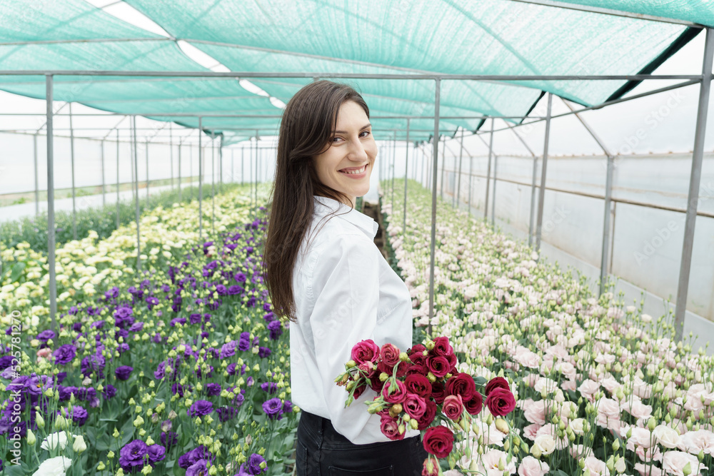 Businesswoman holds a beautiful bouquet in the green house. Woman portrait with flowers. Female florist has an order for fresh flowers.