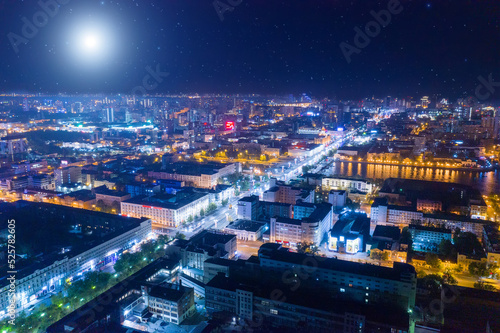Aerial view of the night modern city. Bright moon and lights of the night streets