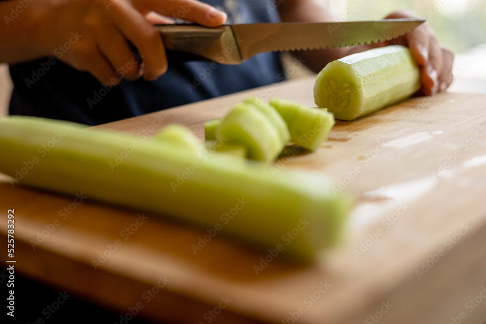 cutting cucumber at home on wooden board close up