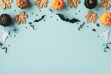 Halloween frame with party decorations of pumpkins, bats, ghosts, spiders on blue background from above. Happy halloween card in flat lay style.