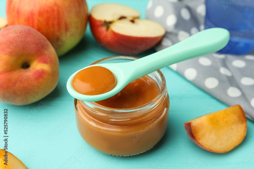 Spoon with healthy baby food and glass jar on turquoise wooden table, closeup Spoon with healthy baby food and glass jar on turquoise wooden table, closeup