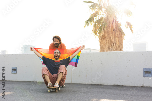 Gay couple embracing and showing their love with rainbow flag. LGBT community.