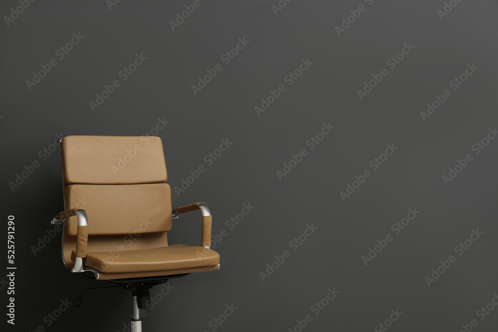 Fototapeta premium Comfortable office chair on black background. Space for text