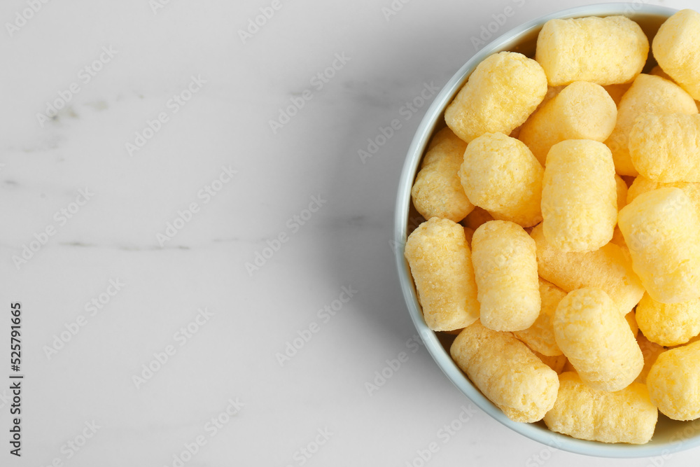 Bowl of delicious crispy corn sticks on white marble table, top view. Space for text Bowl of delicious crispy corn sticks on white marble table, top view. Space for text