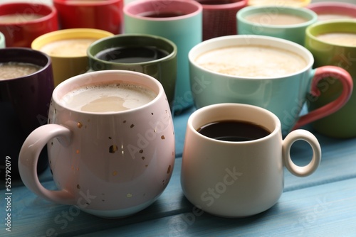Many cups of different coffee drinks on light blue wooden table