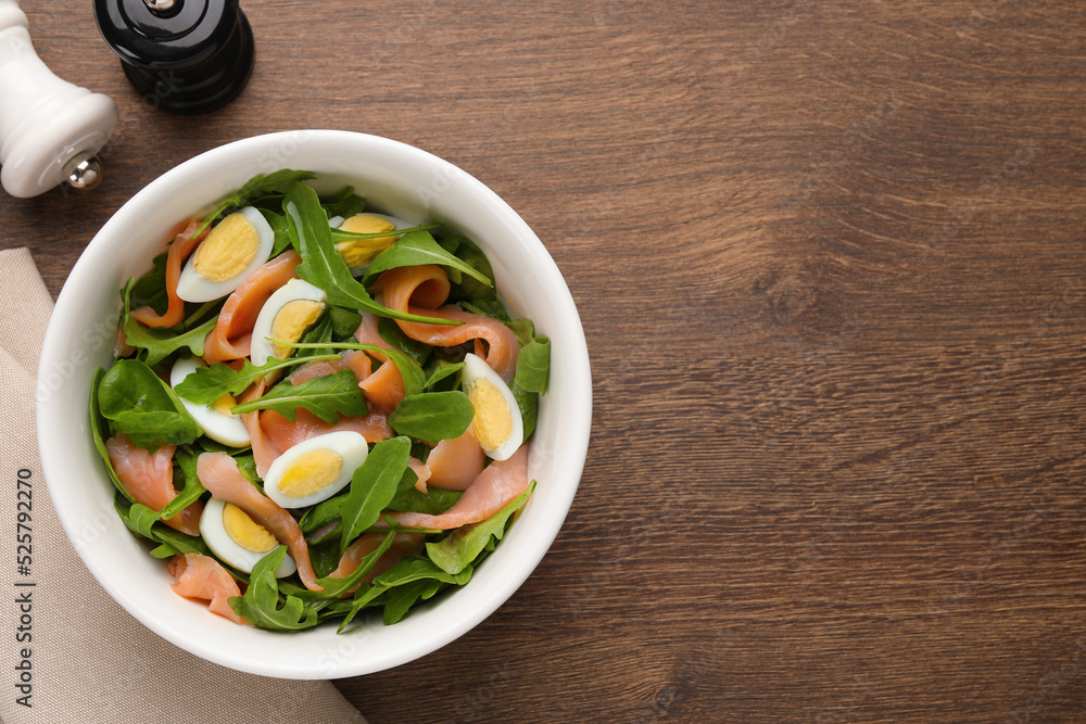Delicious salad with boiled eggs, salmon and arugula on wooden table, flat lay. Space for text Delicious salad with boiled eggs, salmon and arugula on wooden table, flat lay. Space for text