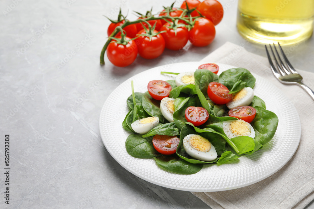 Delicious salad with boiled eggs, tomatoes and spinach on light grey table Delicious salad with boiled eggs, tomatoes and spinach on light grey table