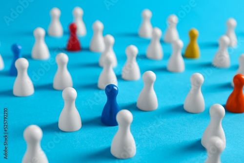 Colorful pawns on light blue background, closeup. Social inclusion concept