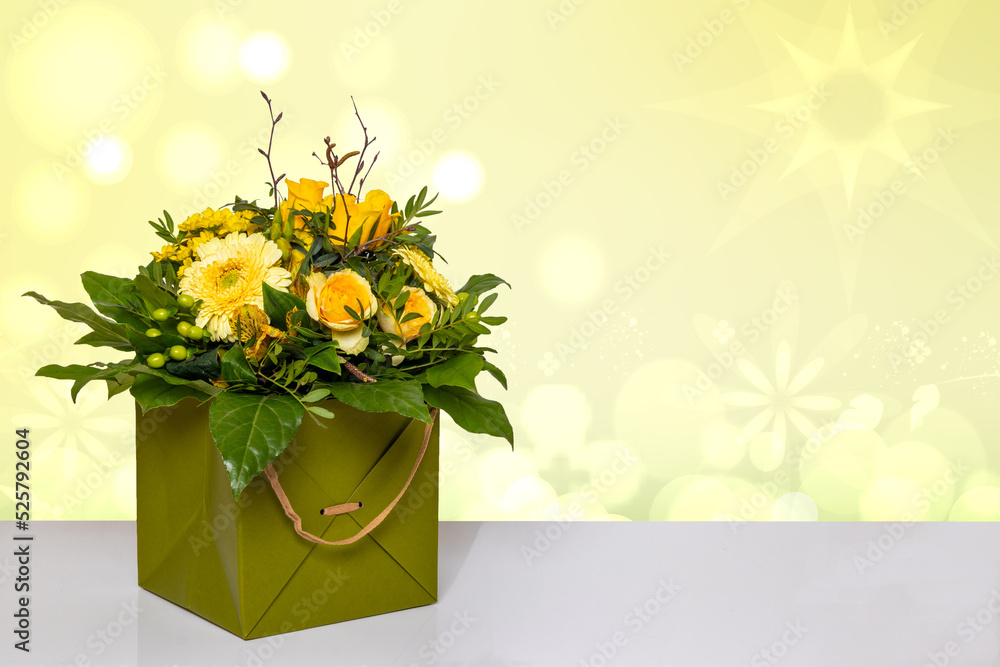 Closeup of a beautiful bouquet of yellow flowers in a decorative green gift box on a bright table over a abstract spring background. Macro. Space for design. Card concept.