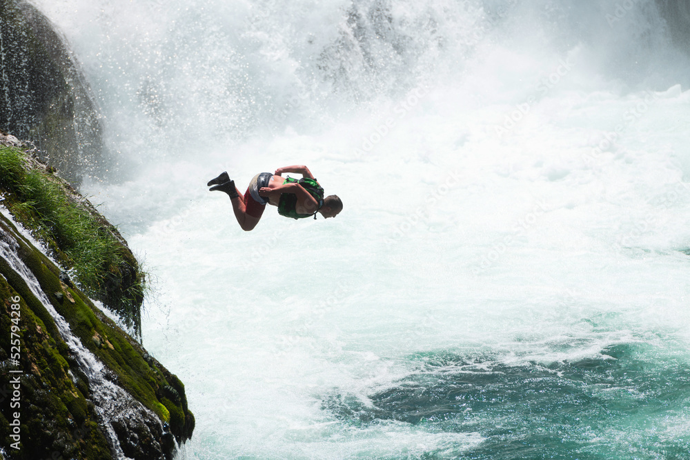 waterfall extreme brave man as superhero running jump and dive from the rock into the wild river water.