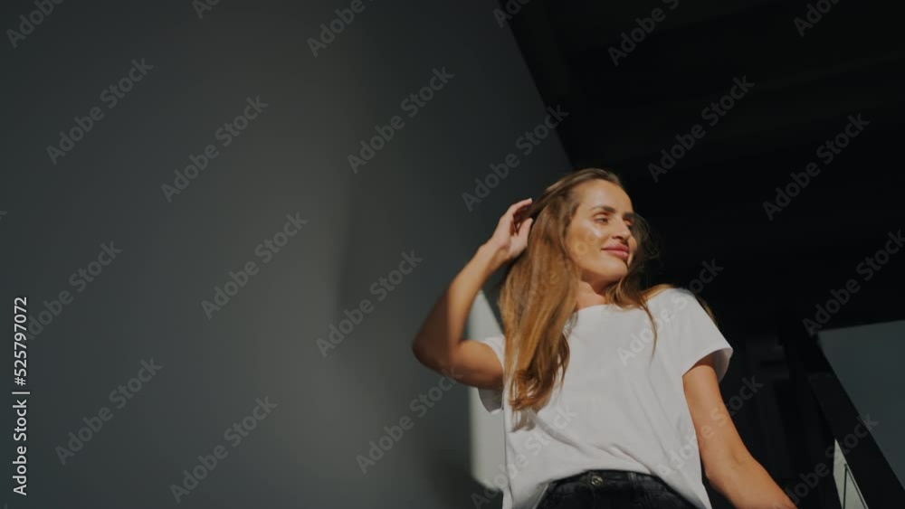 A woman descends in a large bright apartment along the back stairs from the second floor of the bedroom early in the morning, barefoot, at dawn. A large curtain rises, rays sun draw wall from steps A woman descends in a large bright apartment along the back stairs from the second floor of the bedroom early in the morning, barefoot, at dawn. A large curtain rises, rays sun draw wall from steps