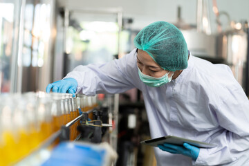 Woman worker checking product bottles on the conveyor belt in the beverage factory. Manufacturer and Inspection quality control