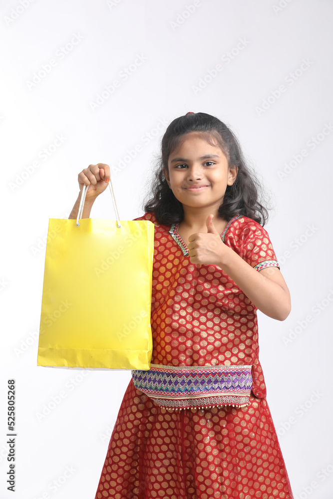 Indian little girl holding shopping bag and giving expression on white background.