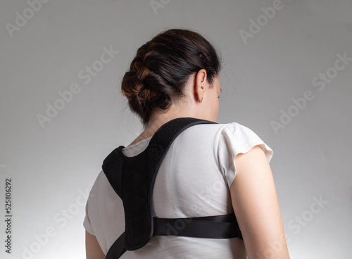 Woman in black posture corrector and fixation brace for the thoracic spine, close-up. Treatment of chronic back pain, osteochondrosis, orthopedic corset photo