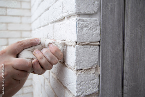 filling the seams in a decorative white stone in the form of a brick on the wall. Laying decorative stone on the wall, close-up