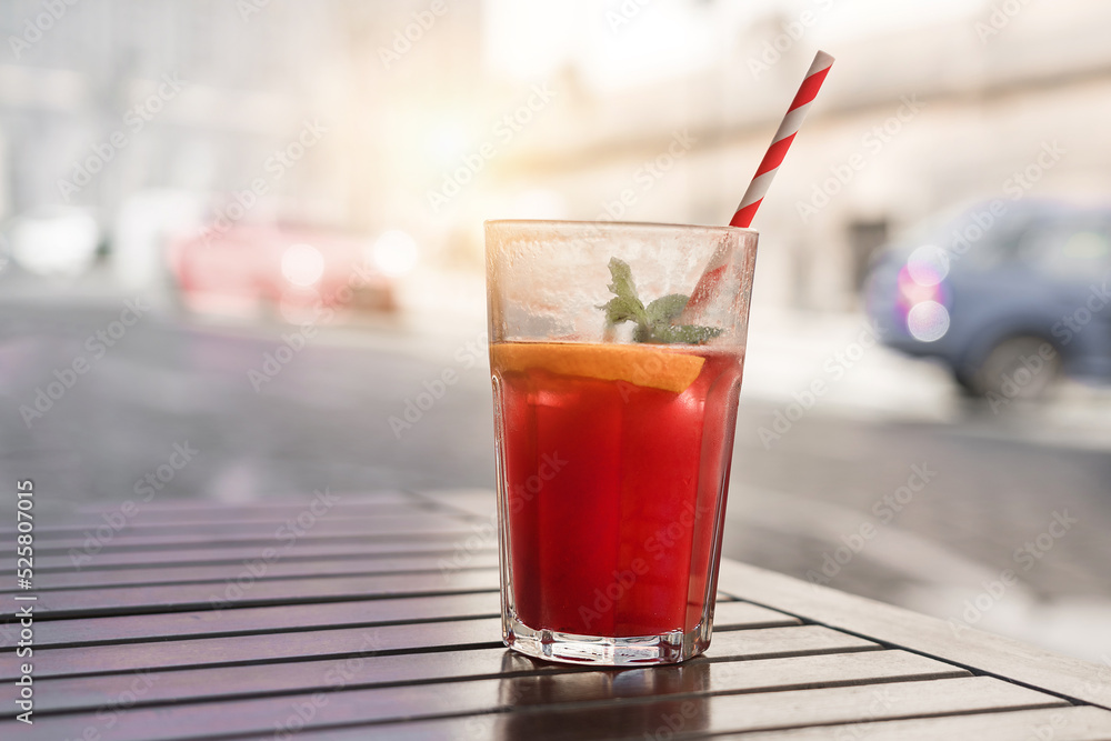 Fresh fruit coctail with drinking straw stands on wooden table of street cafe outdoor Fresh fruit coctail with drinking straw stands on wooden table of street cafe outdoor