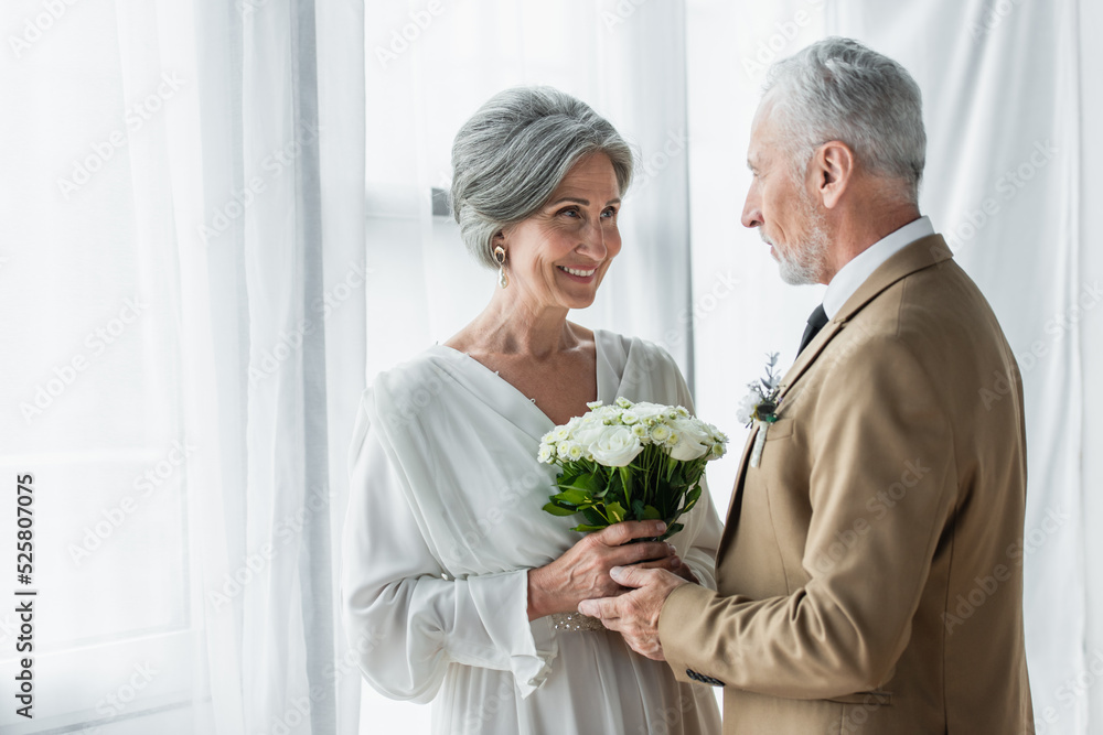bearded middle aged groom giving wedding bouquet to happy bride in white dress bearded middle aged groom giving wedding bouquet to happy bride in white dress