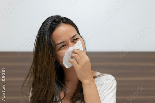 Woman sneezing in tissue at home.