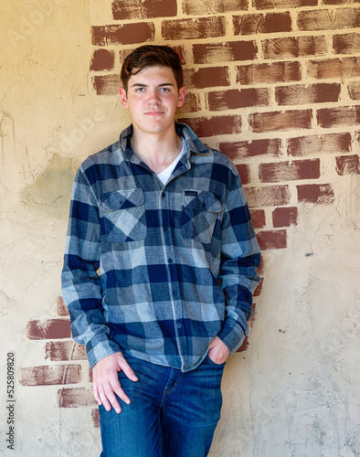 Handsome young man standing in front an old brick wall looking confident and relaxed..