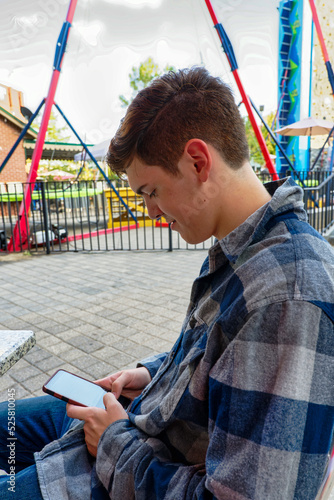 Handsome young man sitting and texting on his cellphone