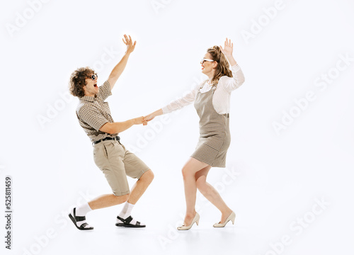 Excited young couple of dancers in vintage retro style outfits dancing lindy hop isolated on white background. Timeless traditions, 60s ,70s american fashion style.