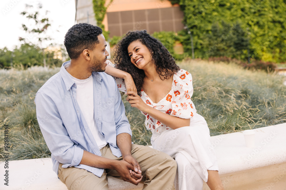 Obraz premium Pretty young african guy and girl enjoy spending time together on street. Brunettes wear casual summer clothes. Good mood concept