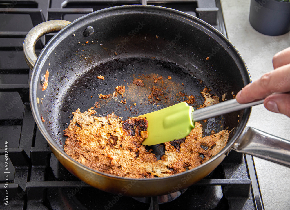 A spatula for stirring food picks off burnt food in a pan. Poor