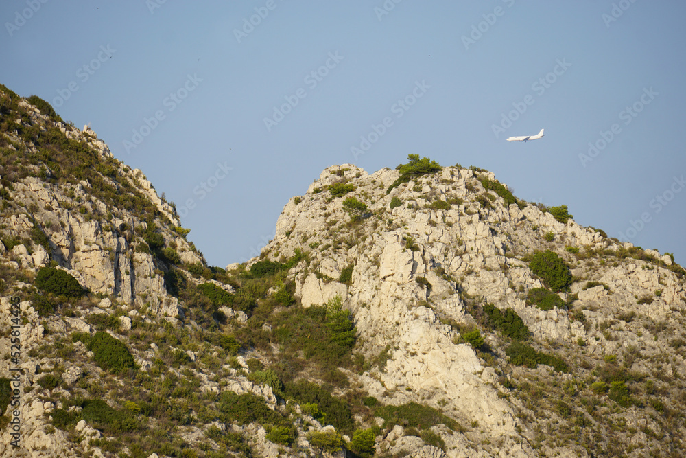 lone plane flying low near the rocky  mountain shore of the calanques, france