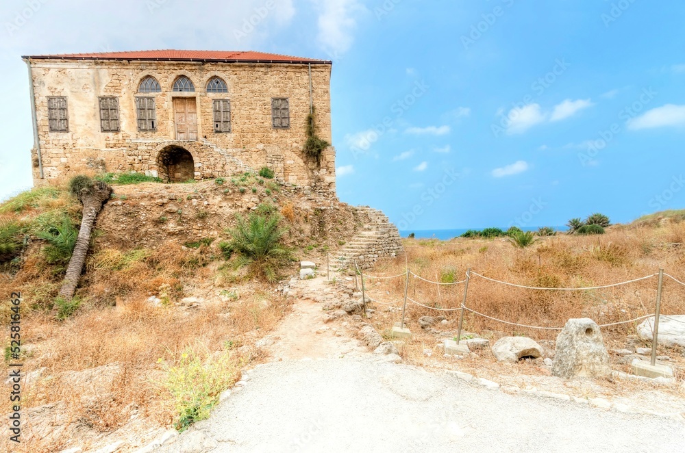An abandoned traditional Lebanese house in Byblos, Lebanon. View of the colonial architecture with terracotta tile roof and limestone facade. 