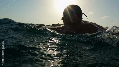 Athletic Young man professional triathlon swimmer practicing at morning sea. Ocean swim slow motion shot