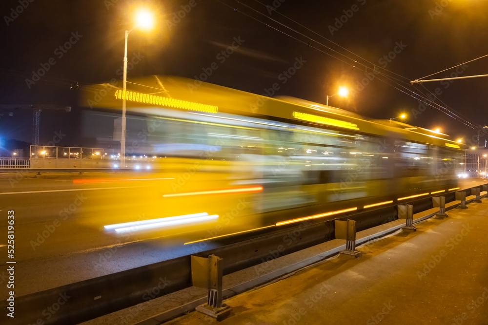 A blurred bus moves along the overpass in the evening.