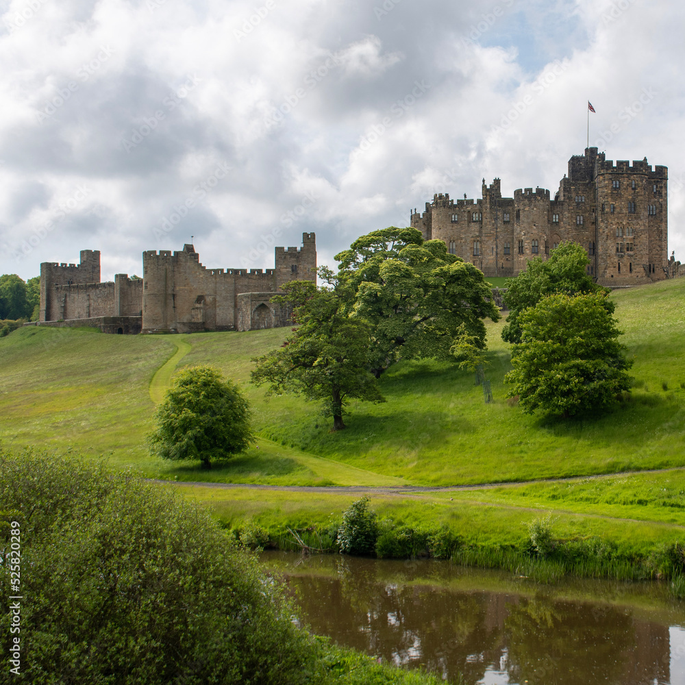 Alnwick Castle reflected in the water of the River Aln. Northumberland, UK