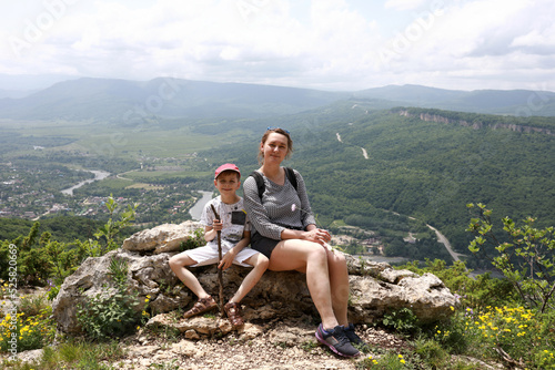 Mother with her son resting on rock of Una-koz ridge in Caucasus