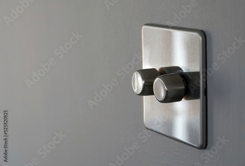 An energy saving stainless steel double dimmer light switch on a grey internal wall of a home.  photo