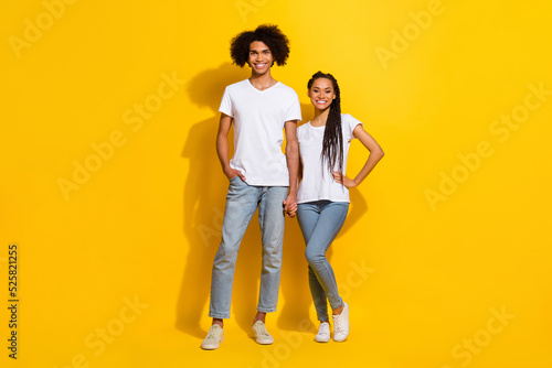 Full size photo of two positive cheerful partners hold hands have good mood isolated on yellow color background