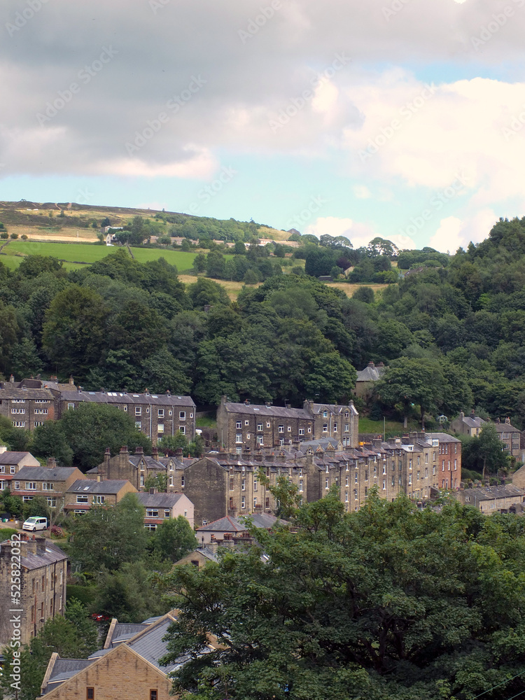 scenic view of rows of typical tall stone houses between hillside trees in hebden bridge west yorkshire