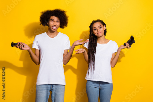 Obraz na plátně Photo of two unsatisfied unlucky people shrug shoulders hold controllers isolate
