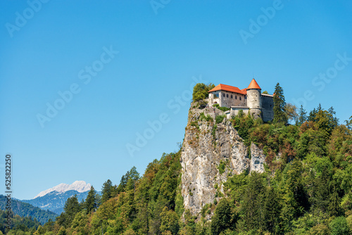 Medieval Bled Castle (Blejski grad), XI century, coast of the Lake Bled (Blejsko jezero). Bled town, Gorenjska, Triglav National Park, Slovenia, Europe. On background, the peak of Triglav or Tricorno.