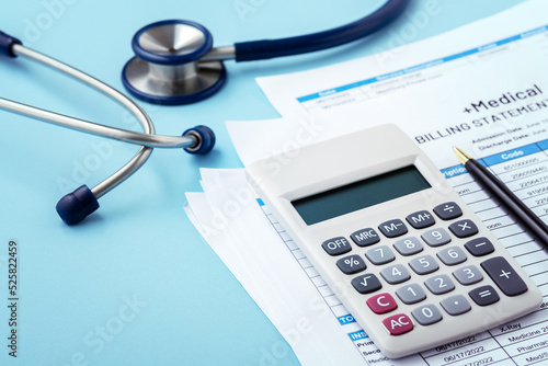Medical bill concept with calculator and stethoscope on blue background