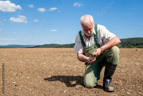 An old, experienced farmer kneels in his freshly sown field and anxiously examines the parched earth. Climate change is hitting farmers hard and there is no sign of improvement.